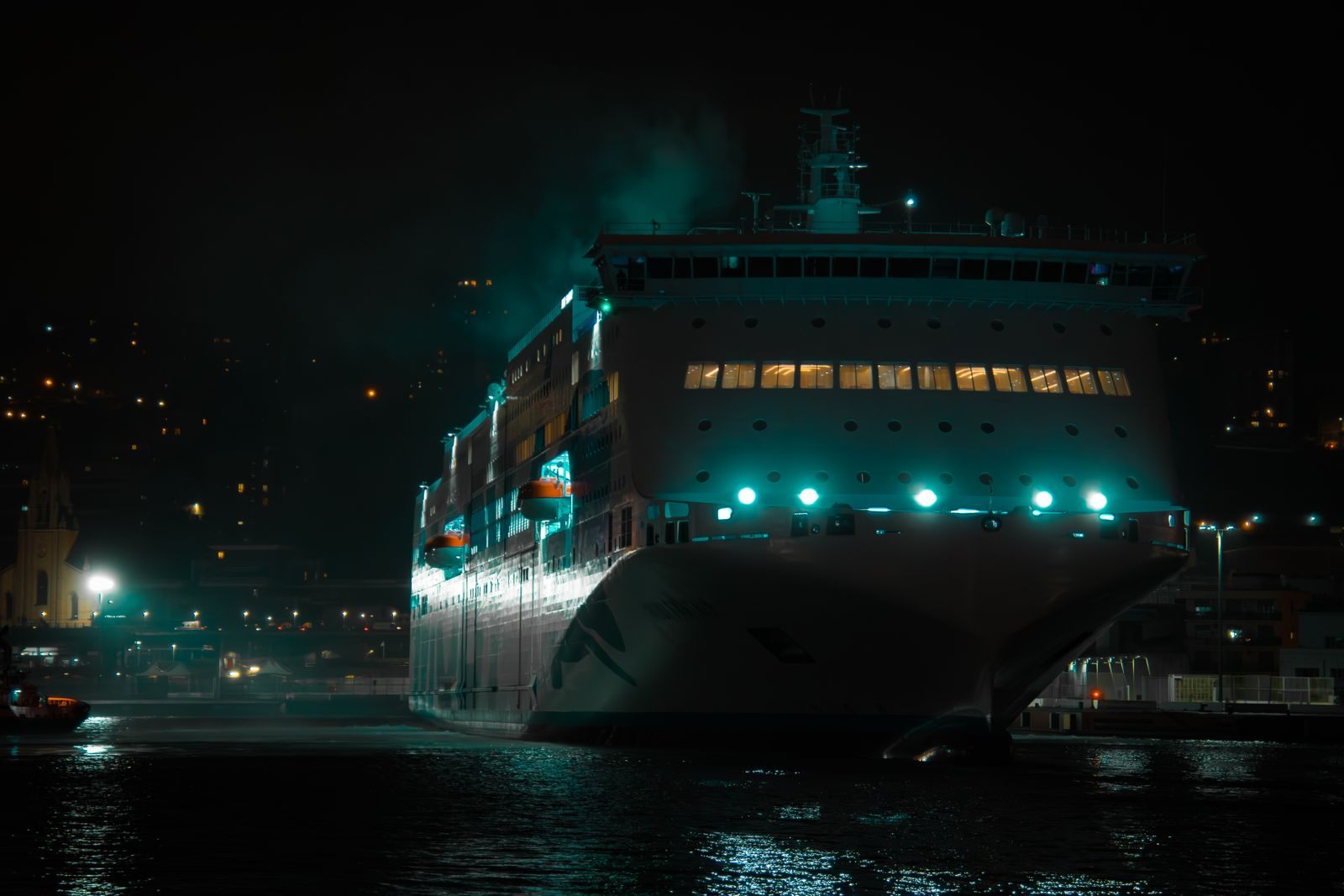 Large ship lit up at night at a quayside
