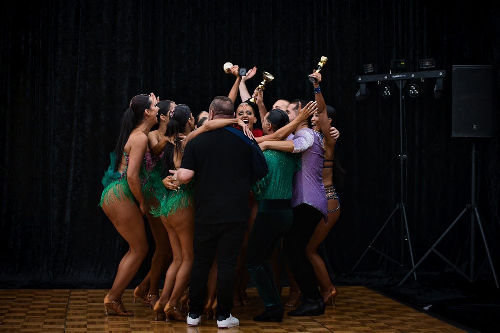 Performers celebrating together on a dark stage