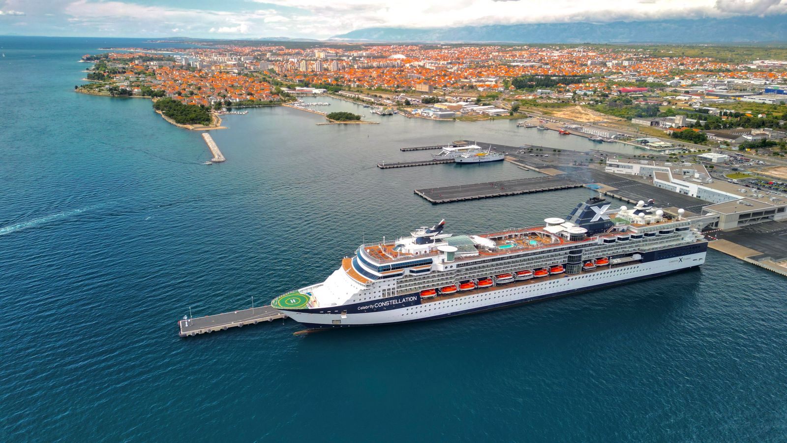 Aerial view of a cruise ship berthed at a pier beside a coastal town