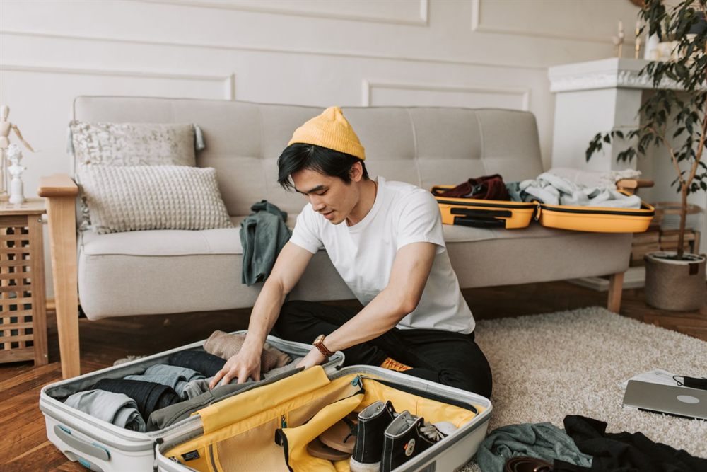Traveler packing a yellow suitcase on a living-room rug