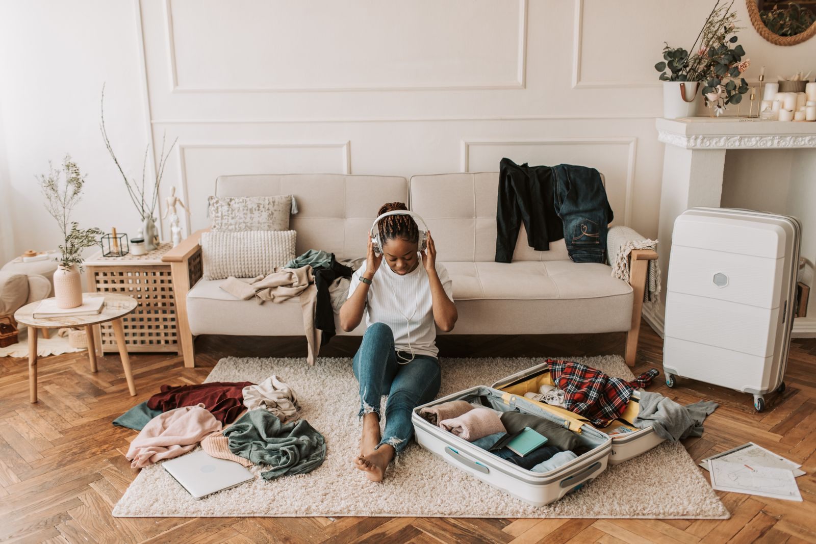 Woman sitting on the floor packing an open suitcase at home